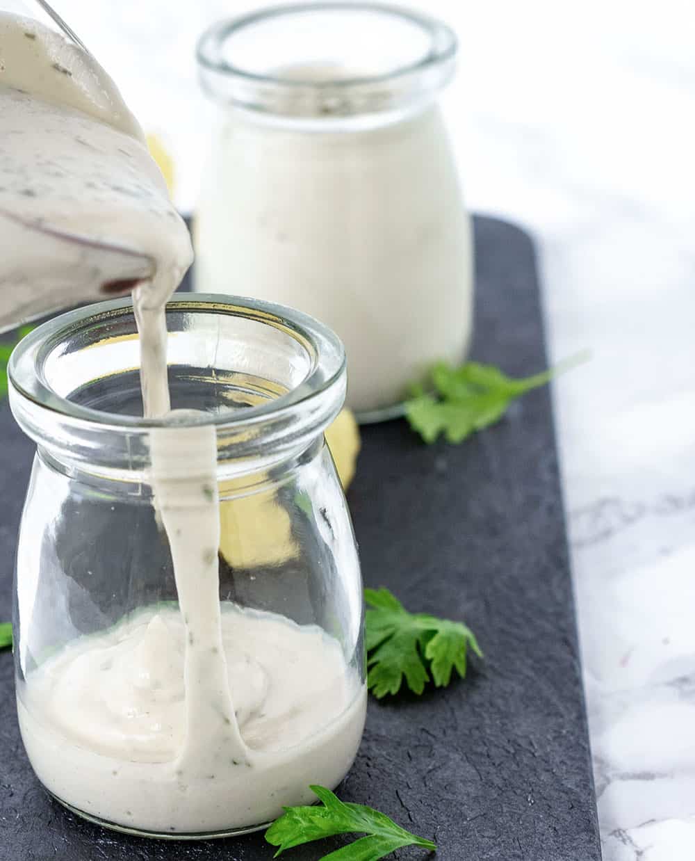 Vegan Ranch Dressing Recipe being poured in a glass jar from a pitcher