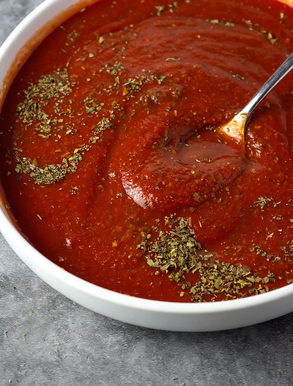 Best homemade pizza sauce being mixed in a white bowl