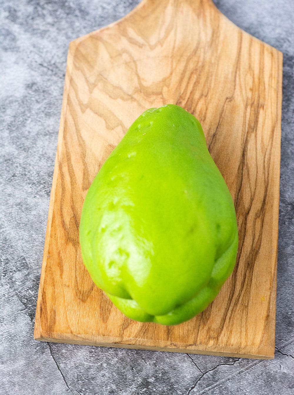 Chayote green skin squash that looks like a pear also called chocho on a cutting board
