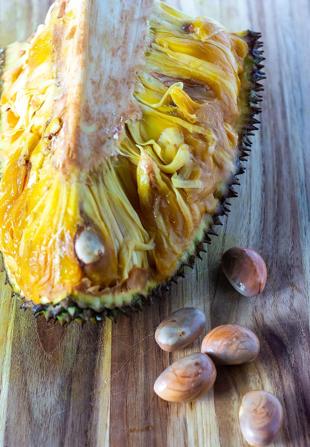 Slice of jackfruit with seeds on cutting board