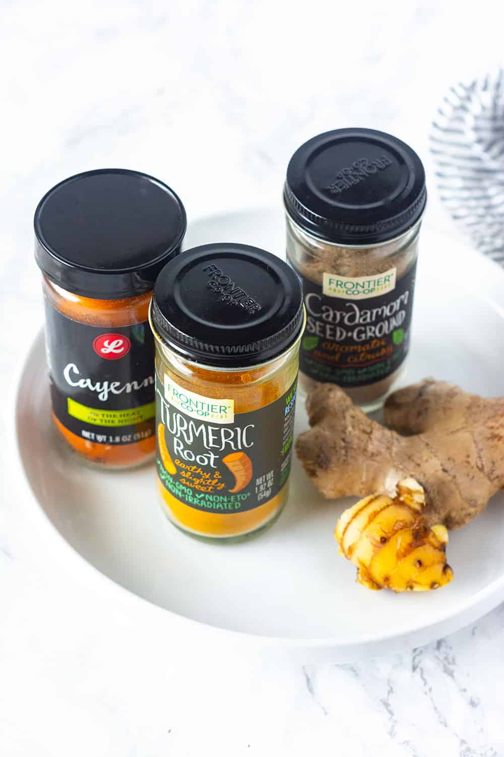Ingredients for golden milk turmeric tea, cayenne pepper, turmeric, cardamom, ginger in spice botttles