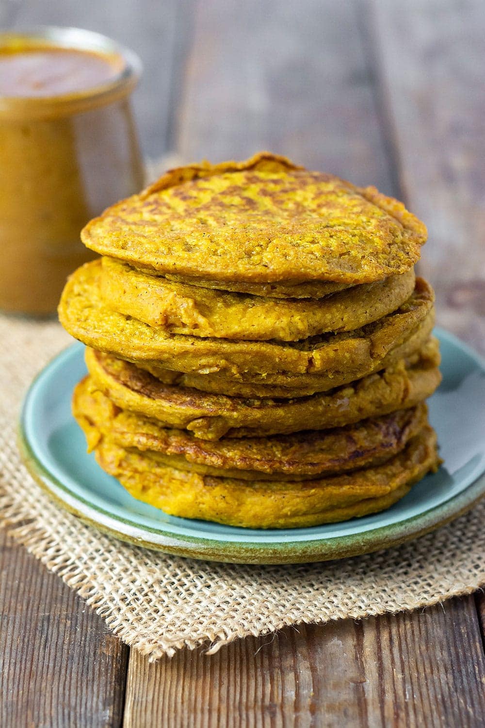 Vegan pumpkin pancakes stacked on a green plate