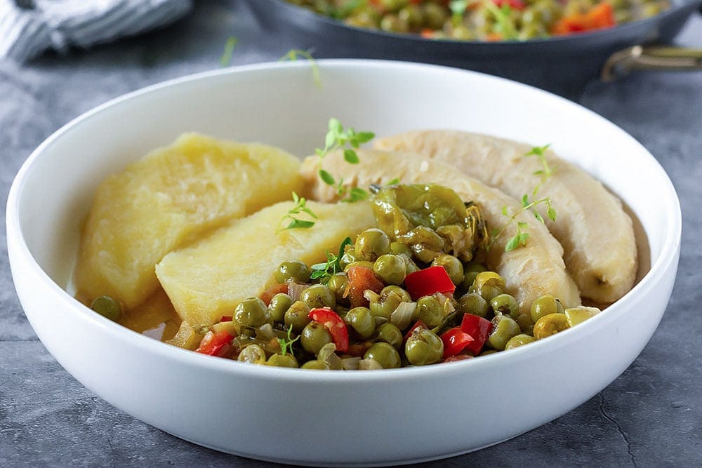 Susumba stew recipe in a bowl, yellow yam, green banana in a white bowl on a stone background