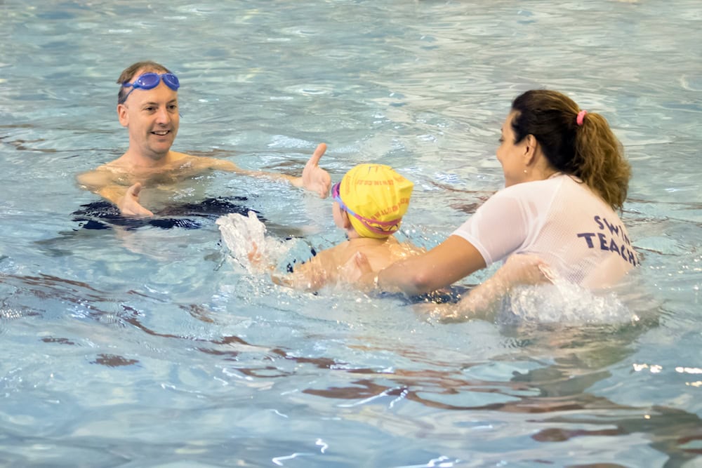 a child learning to swim with a swim teacher