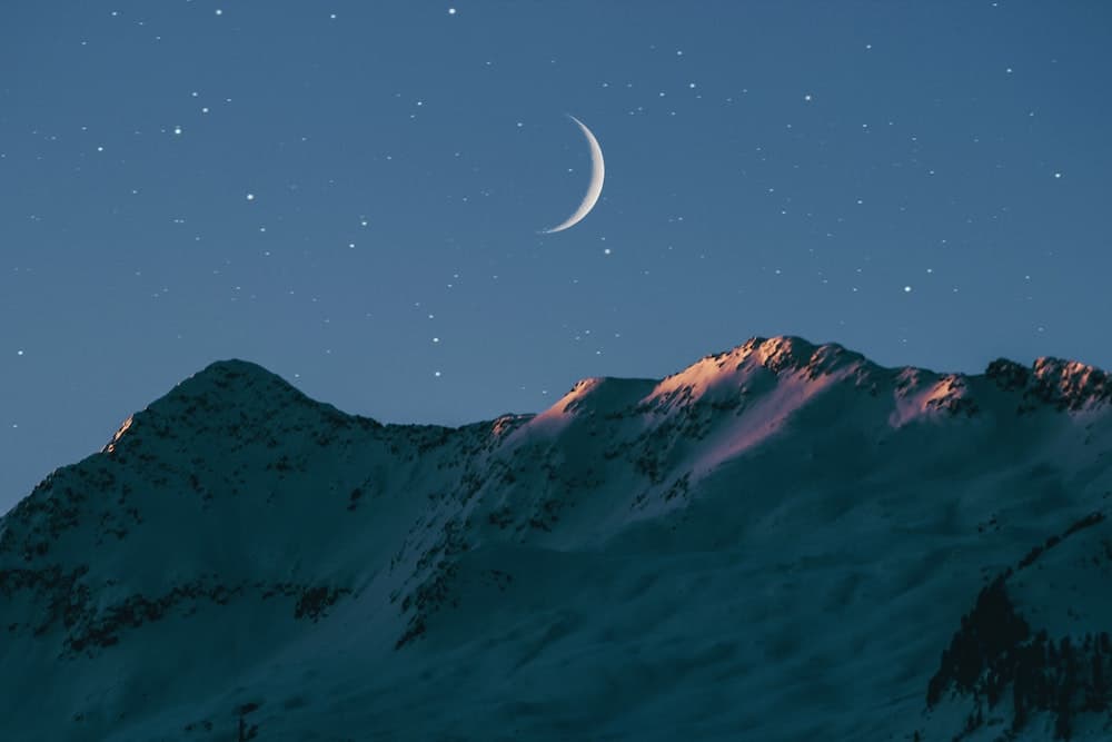 crescent moon in a mountain landscape with stars