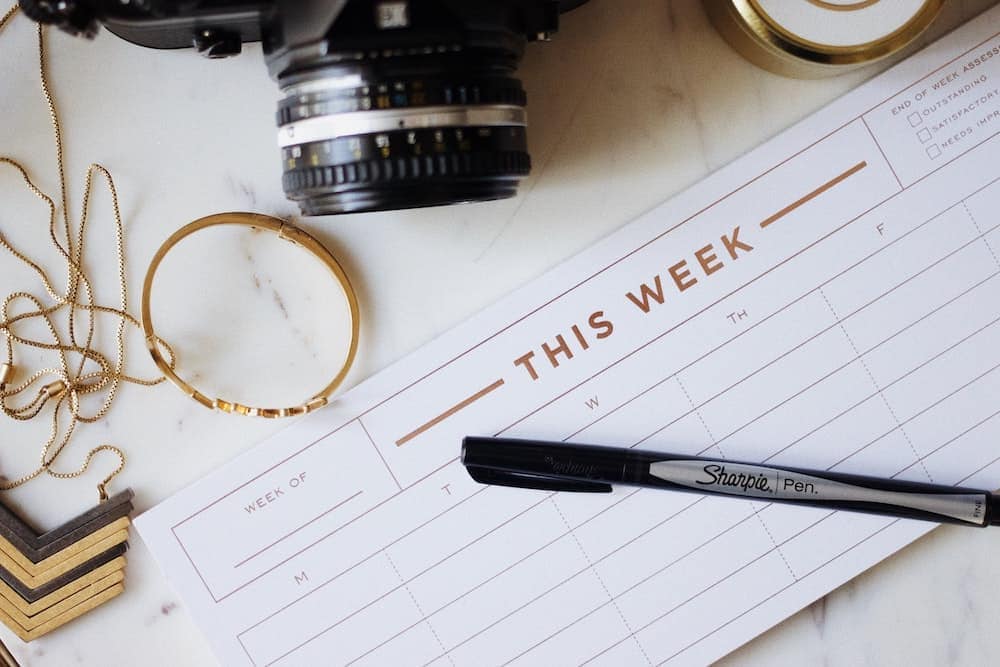 weekly planner surrounded by a pen and a camera