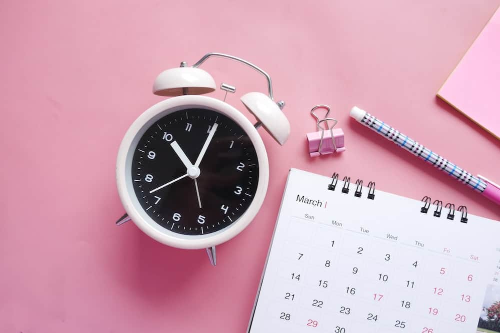 planner next to a clock, pen and stationery accessories