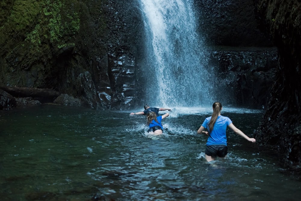 A couple people diving into the frigid water underneath lower oneonta falls