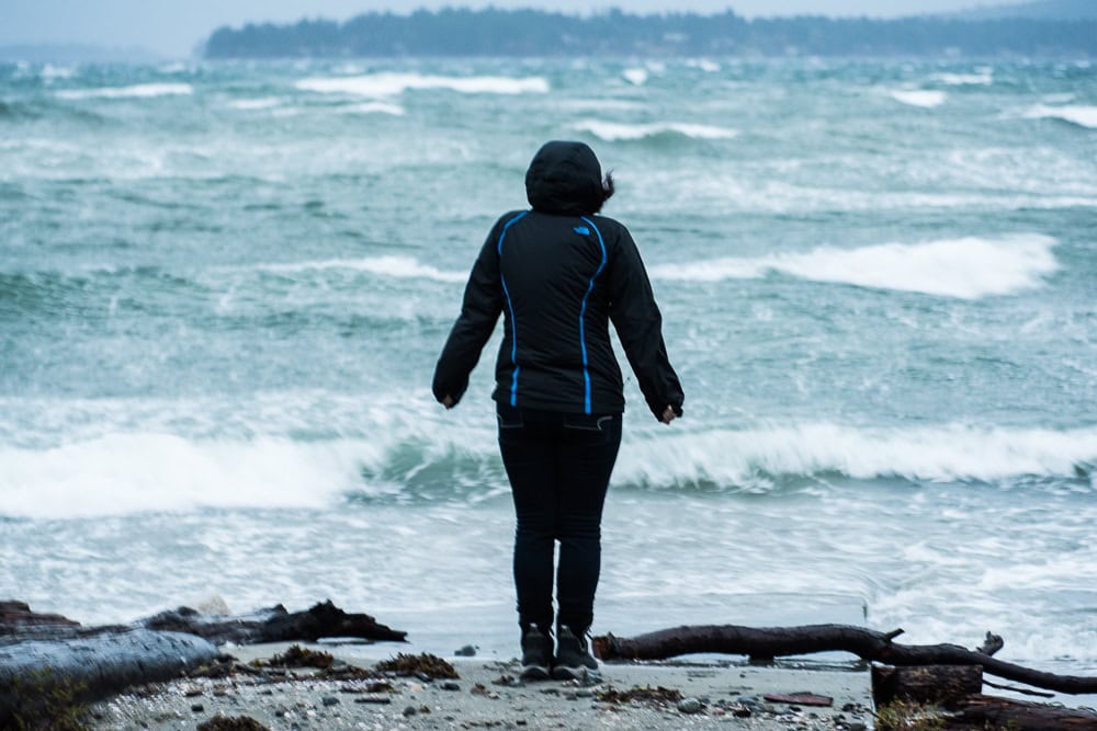 Brooke standing near the shoreline of Rathtrevor beach as powerful storms rolled through making for heavy rain, strong win, and many waves.