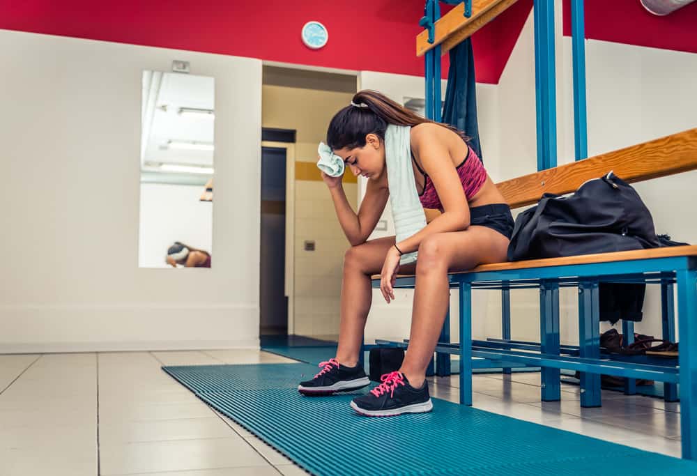 Exhausted athletic girl tries to prevent fitness-related acne due to sweat. 