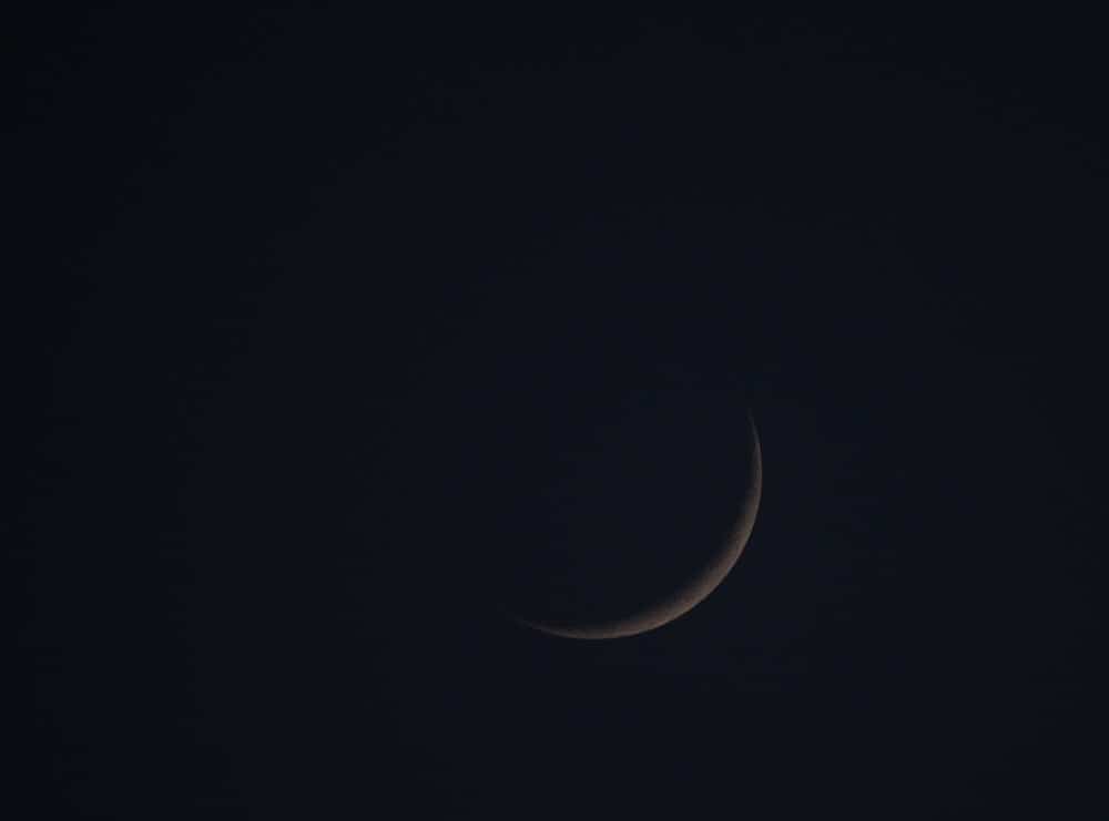 faint outline of the moon on black sky background