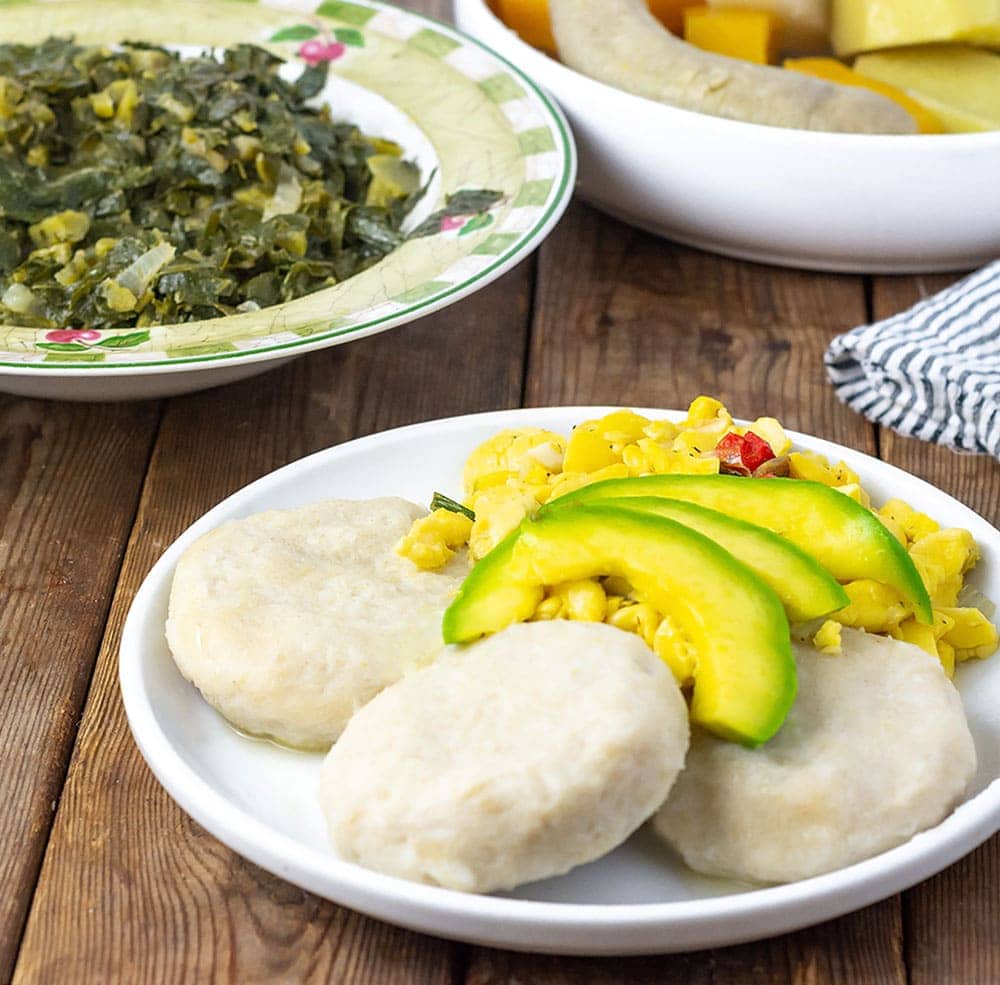 Cassava Dumplings with avocado, and ackee on the plate, collard greens in the badk
