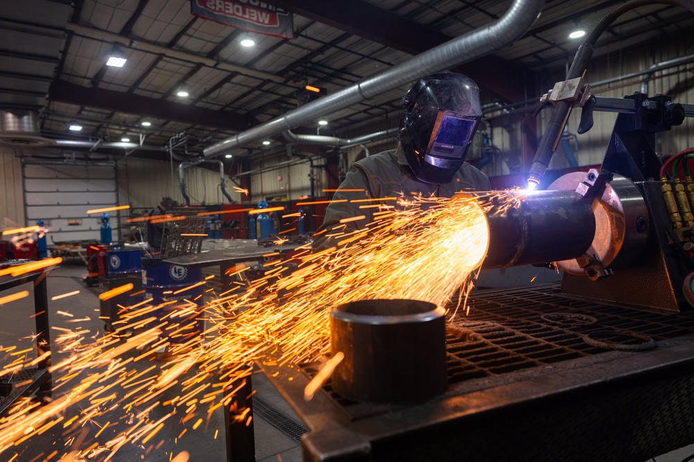Hooded welding student working on fabrication.