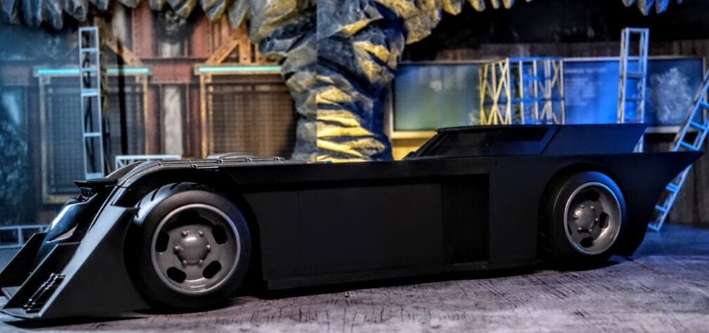 Side profile of McFarlane Toys DC Rebirth Batmobile in Batcave setup.