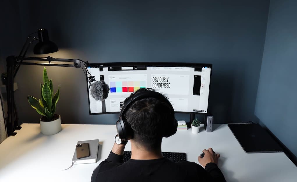 man at desk doing creative work with headphones and microphone