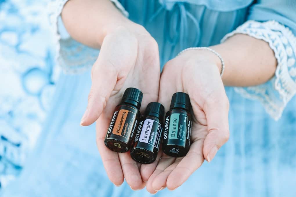 three doterra essential oils in womens hands including frankincense, balance, and lavender essential oil