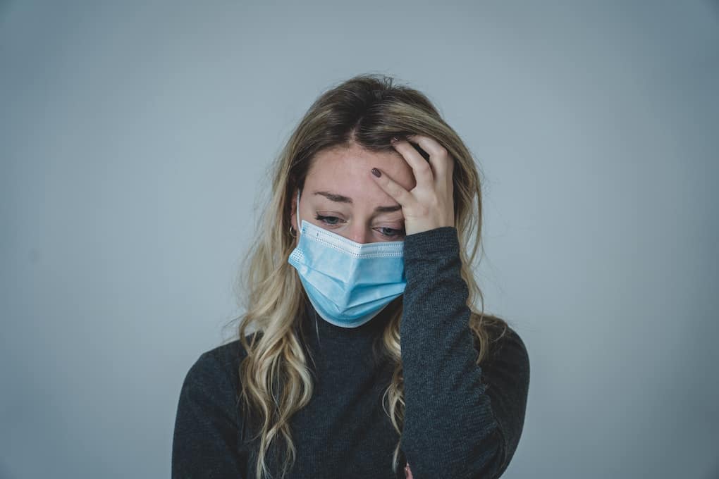 woman looking very anxious wearing medical face mask