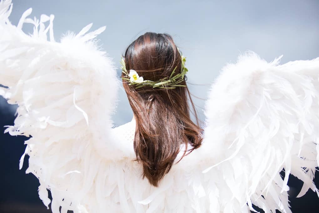 back of woman wearing angel wings and flowers in her hair