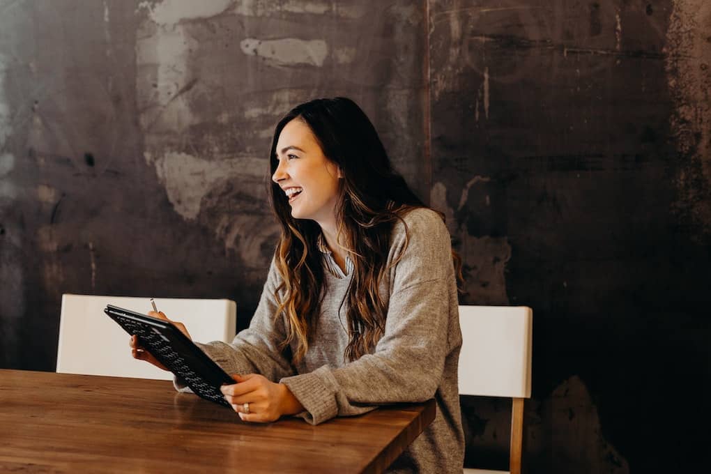 woman smiling at work holding tablet at conference table