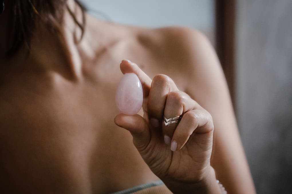 woman holding a rose quartz yoni egg in her hand