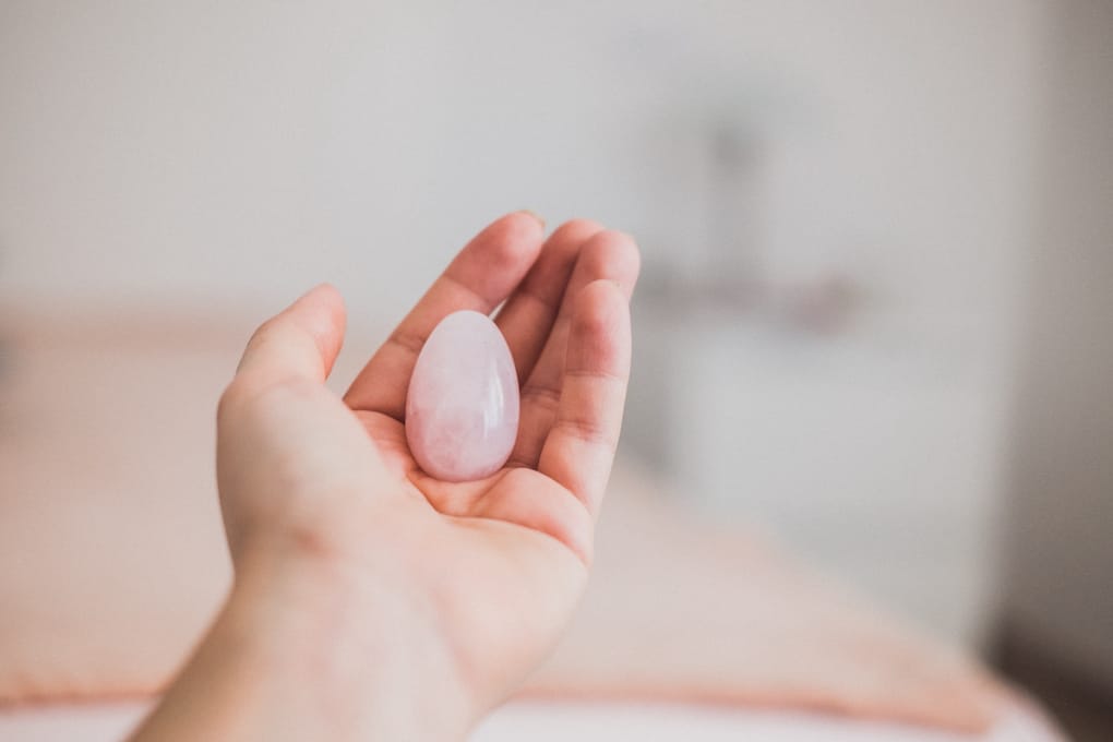 Woman holding a rose quartz crystal yoni egg in her hand