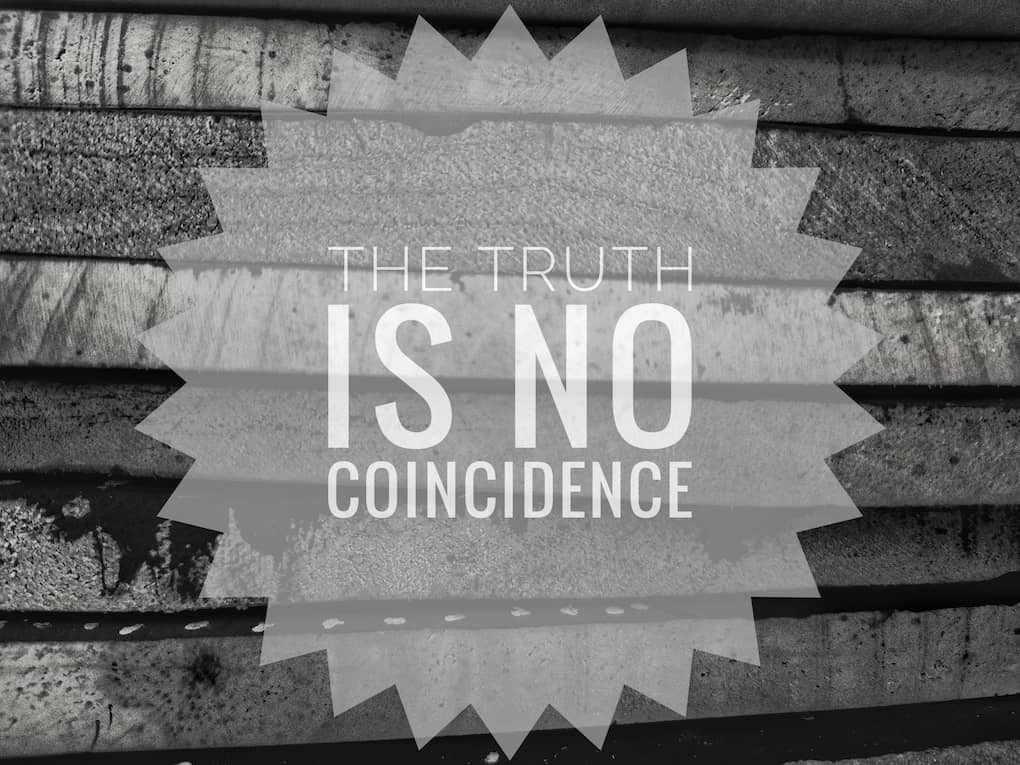 black and white quote on wooden background that reads "the truth is no coincidence"