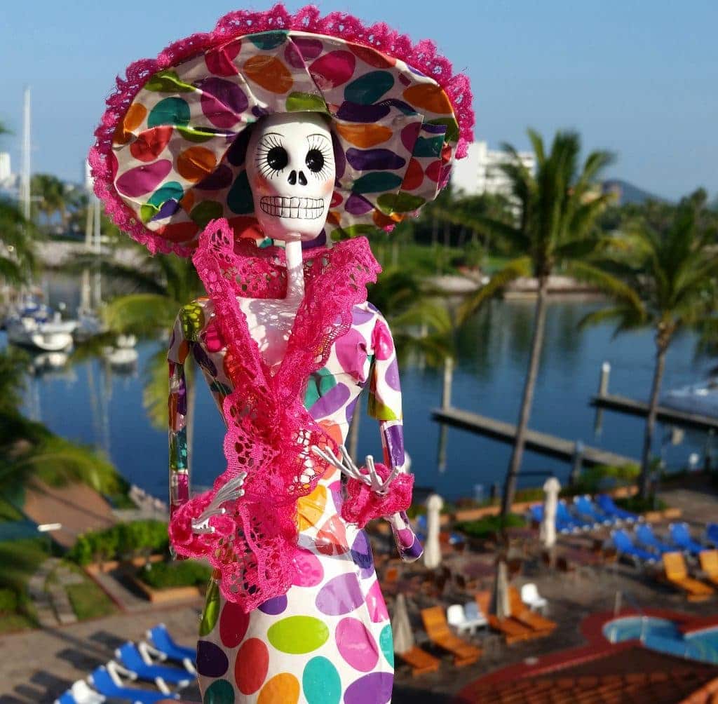 Paper mache Katrina with skeleton face and multi-colored dress and wide brimmed had