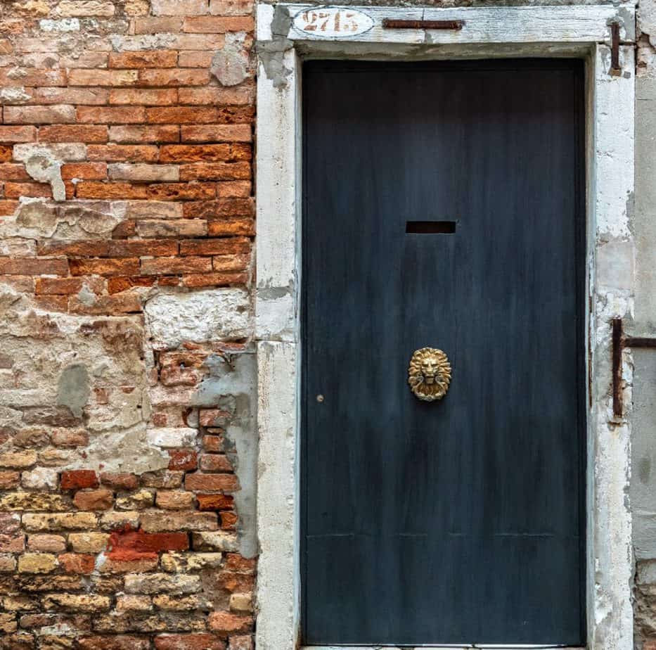2020 interior design trends - black door with antique lion knocker on vintage building with red brick
