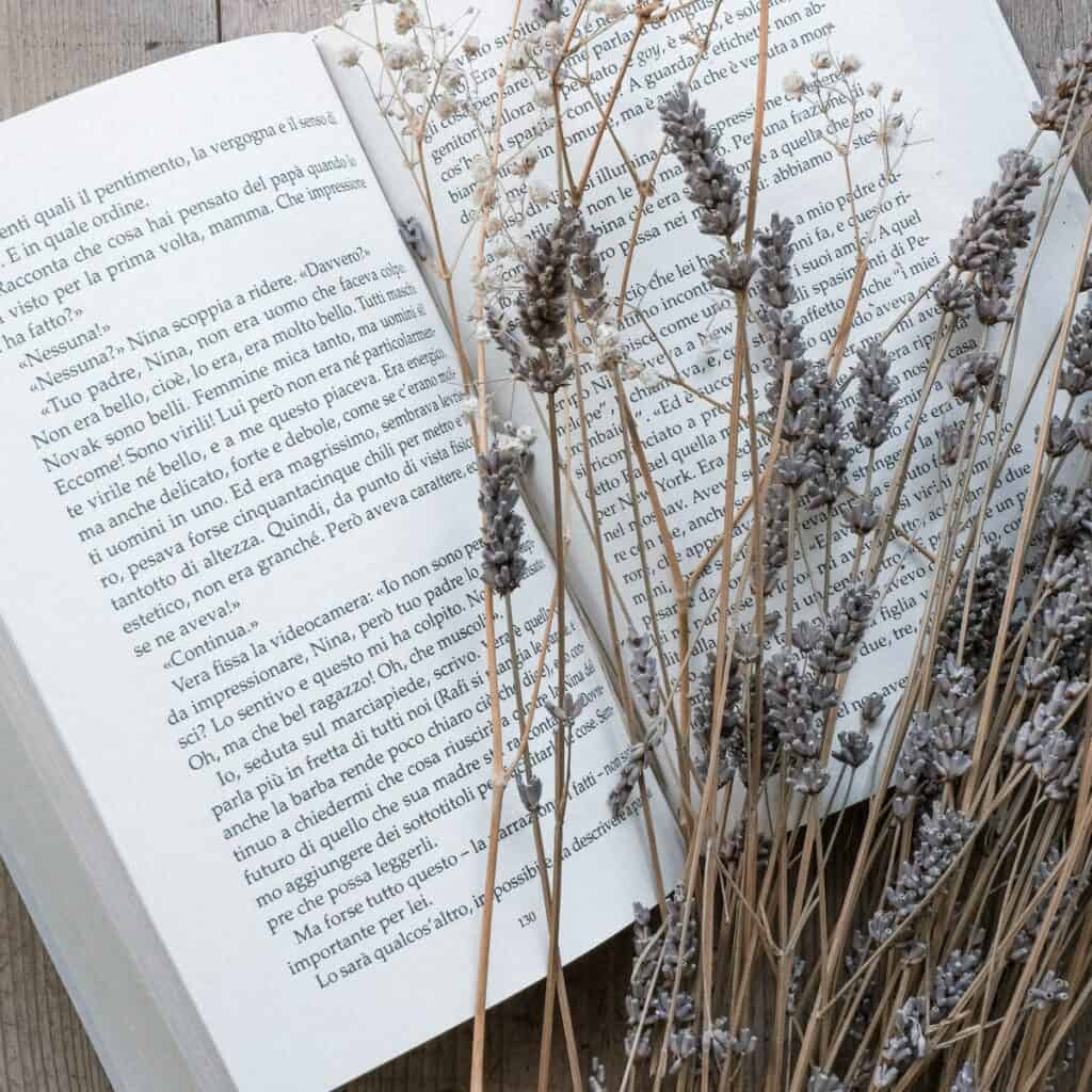 a book placed on a wooden surface with dried lavender on