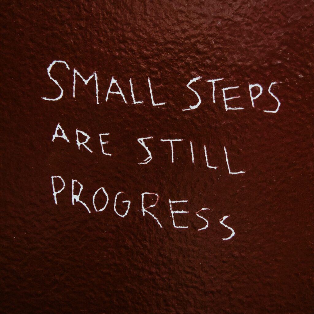 small steps are still progress quote etched on dark red background
