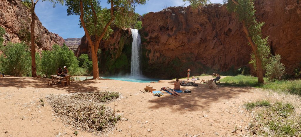 Sandy beach with people laying in the sun - Havasu FAlls in the background