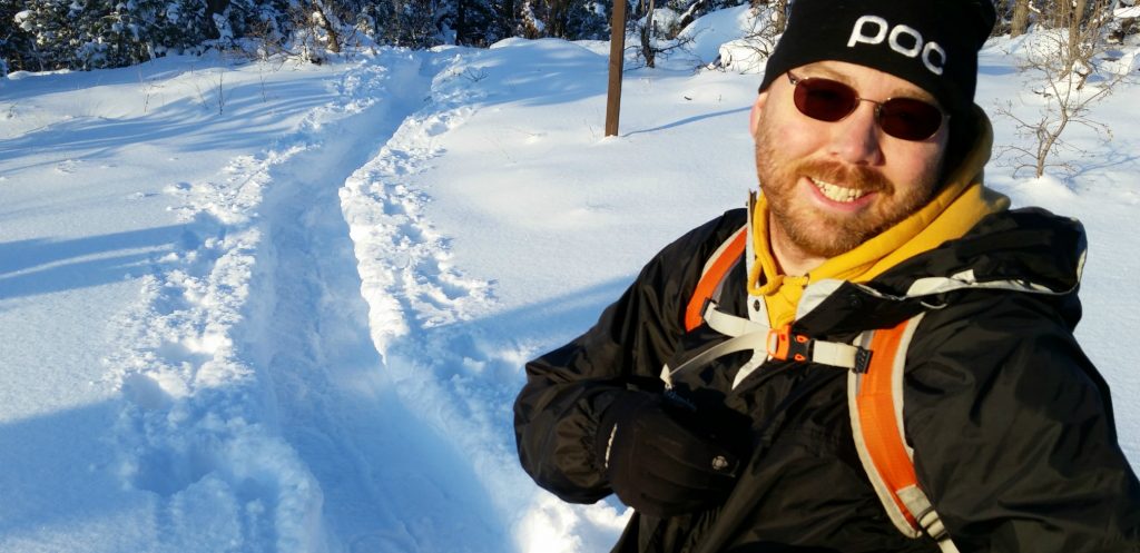 man stands on snowshoe trail with backpack filled with Backcountry Essentials for Hiking & Skiing, the Ten Essentials of Hiking