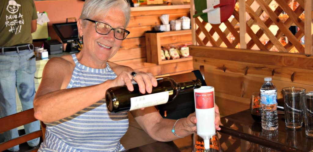 woman holds DiVine Wine Vortex™ Wine Diffuser over wine glass with one hand,and pours wine from wine bottle in other had