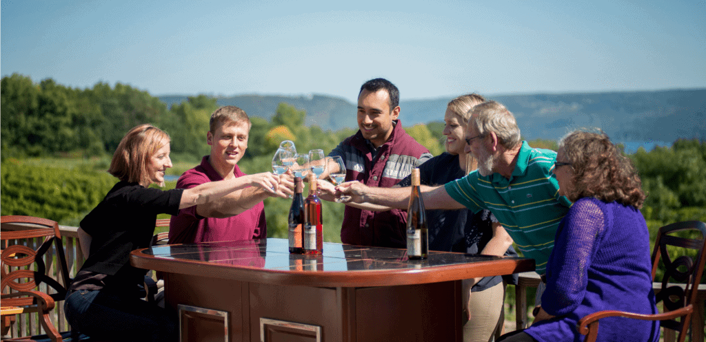 Family of dad, mom and kids and grandma toast wine glasses at one of the best wineries in Finger Lakes