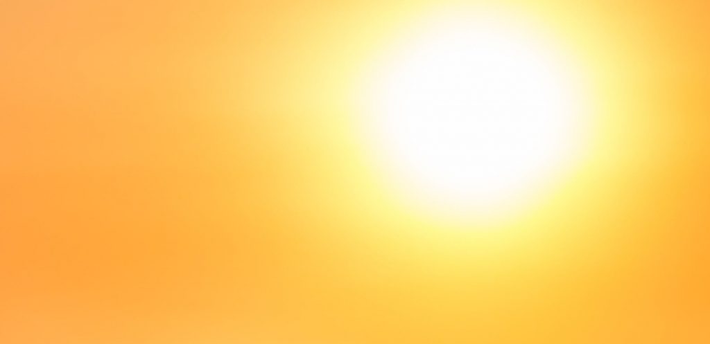white hot sun burns through orange colored sky