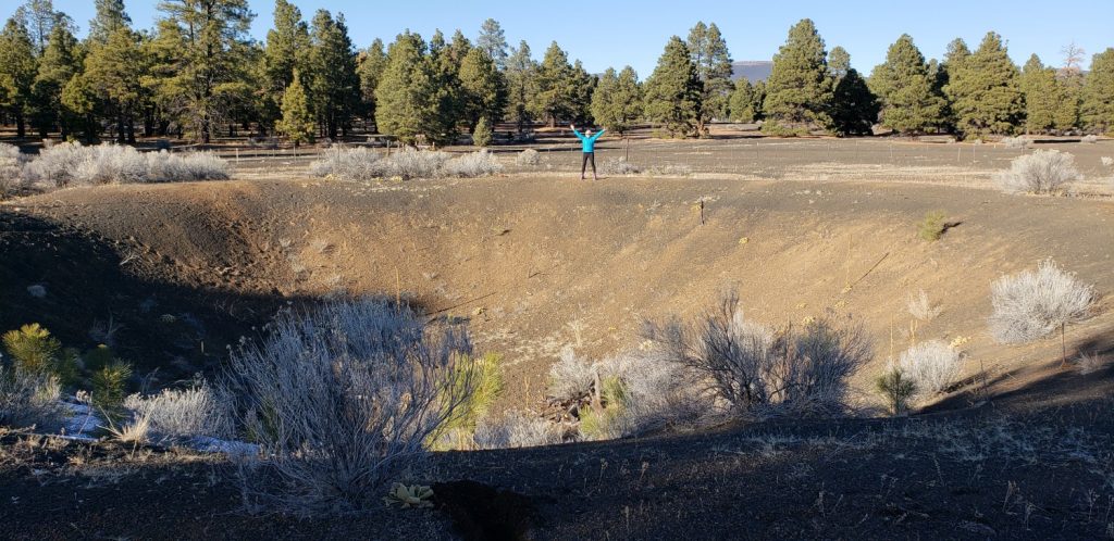 huge crater in cinder field - pin trees in background