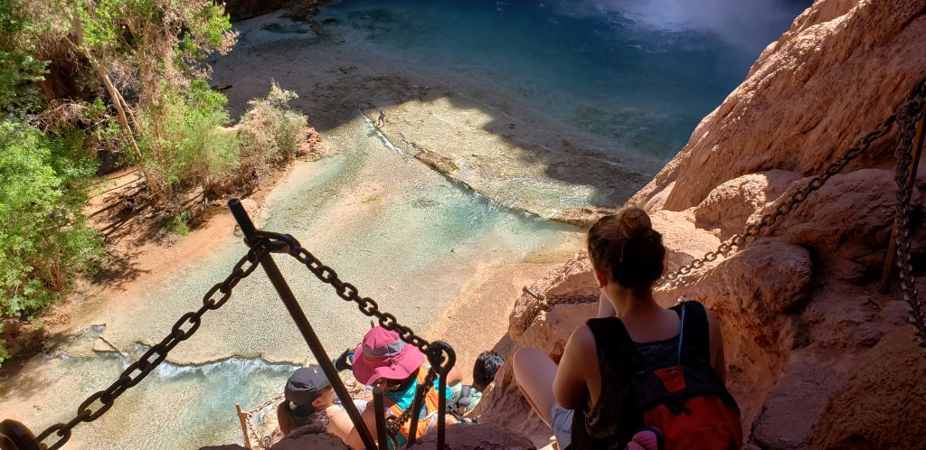 Hikers climbing down steep ladder at Mooney Falls