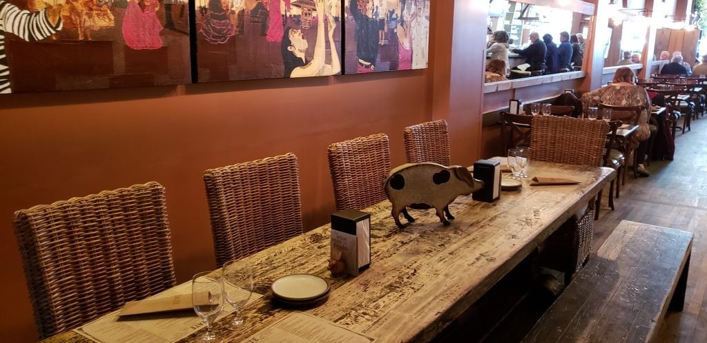 Long rustic table with wood cut out pig as centerpiece of Spanish themed Curate restaurant