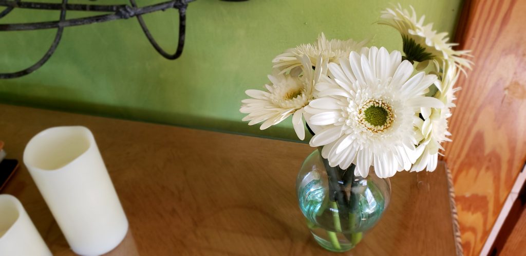Fresh white floers in a clear glass bowl off set by the green walls of the bedroom of this This Property has been placed on the National Register of Historic Places by the US Department of Interior at this Asheville NC B&Bs