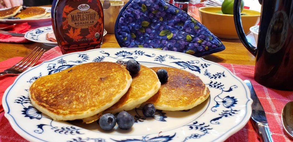Blueberry pancakes on plate with Canadian maple syrup behind