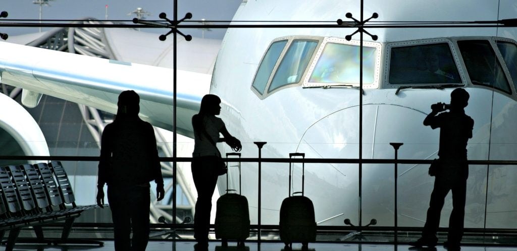 silouetted of woman traveler with best carry on for a woman as she looks at huge airplane at airport. best lightweight luggage for international traveling