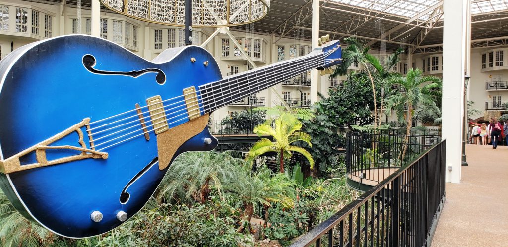 huge blue electric guitar hangs from ceiling with tropical garden below in atrium in Nashville now