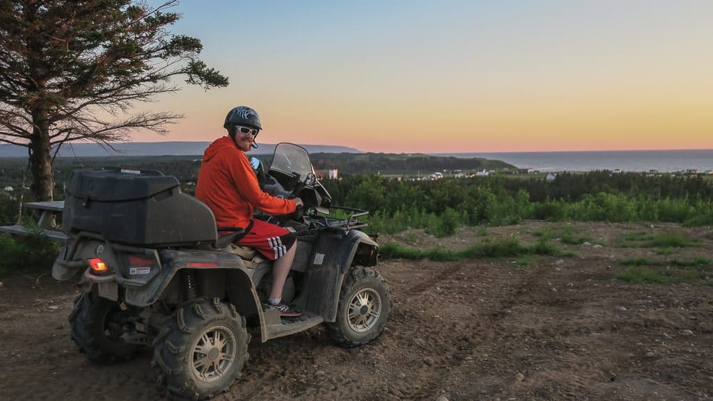 Buddy sitting on the ATV while the sun sets behind him