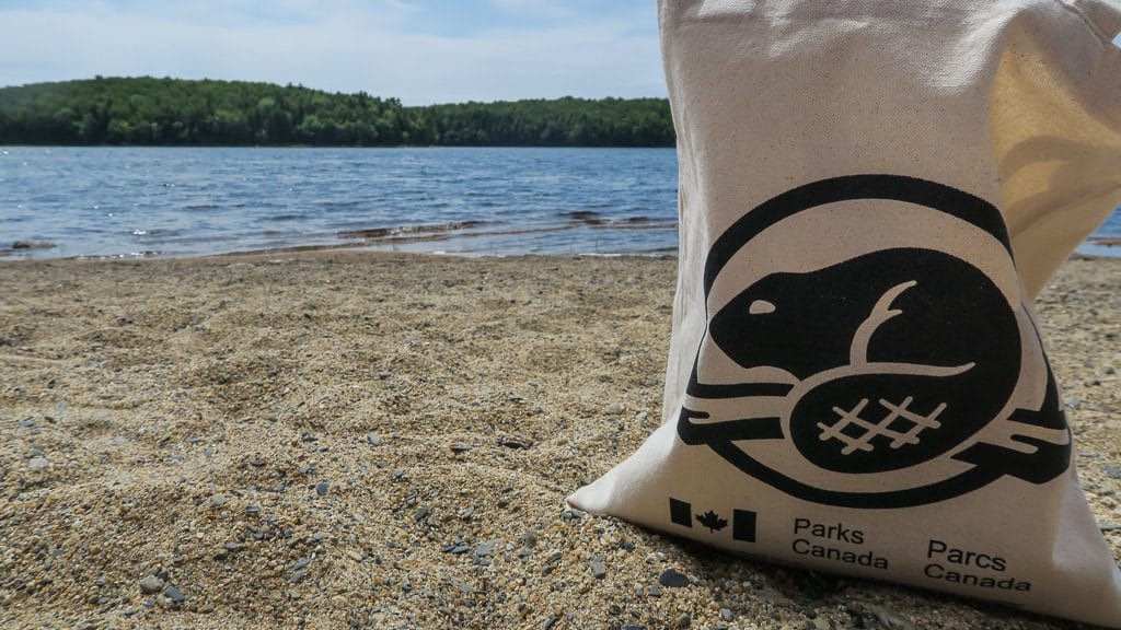 Parks Canada bag sitting on the sand at a beach in kejimkujik national park