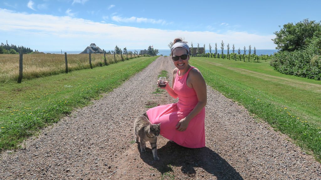 Brooke making friends with a cat at Rossignol Estate Winery while sipping a glass of local wine.