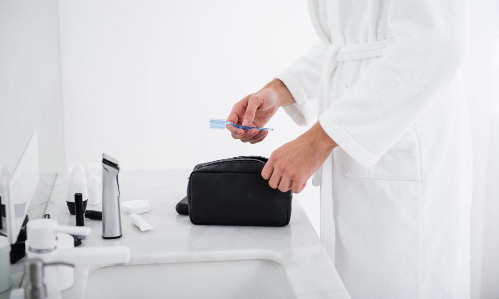 putting travel toothbrush into toiletry bag in hotel bathroom