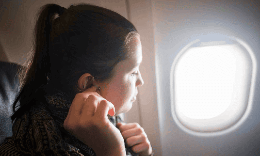 women putting in earplugs on airplane