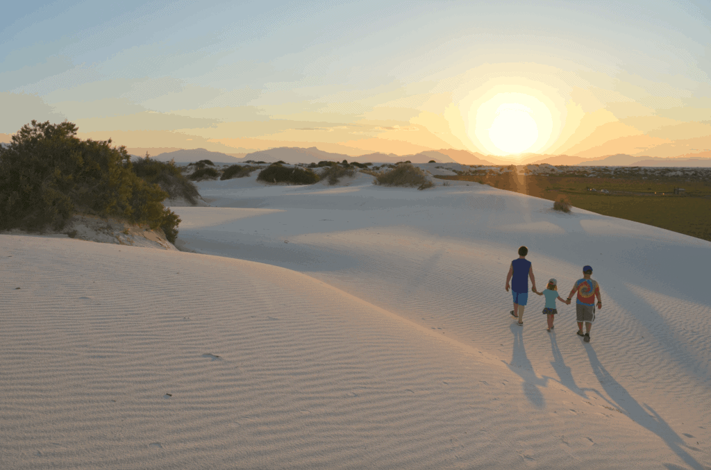 kids holding hand on white sand at sunset