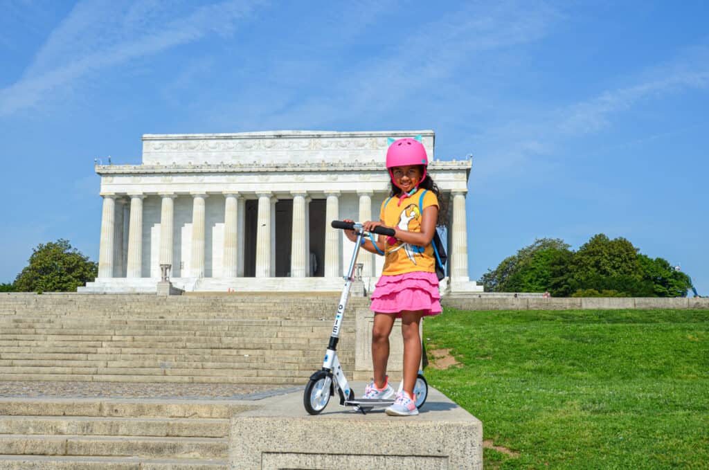 Little girl standing beside a scooter on the steps of the Lincoln Memorial in Washington DC