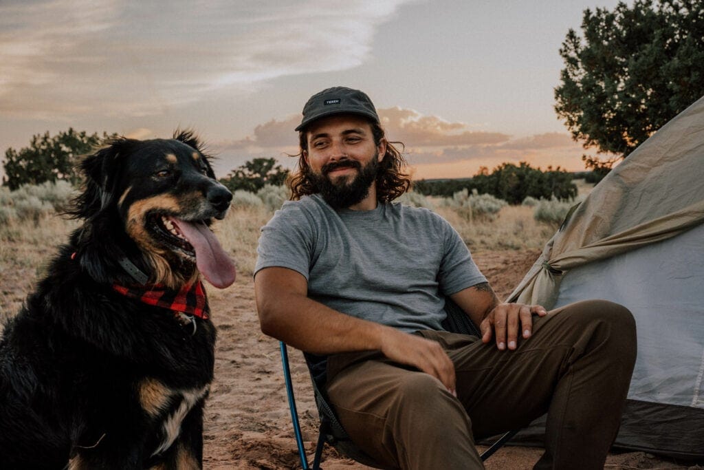 Photo of me wearing TEREN's lightweight traveler pants sitting next to my dog while camping